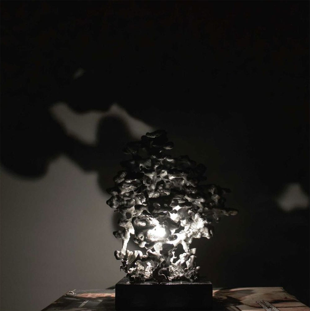 black and white photo of "Colonies" lamp by Mississippi State Interior Design student Marygrace Lee. Lamp is lit and was created the piece by pouring 100% recycled melted aluminum into an ant bed