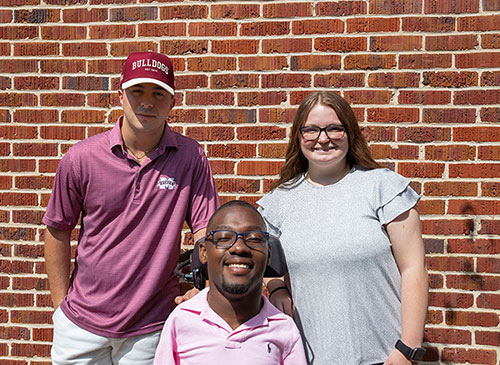 MSU photography seniors posing against brick wall, left to right: Nathan Streeter, Kendrell Daniels and Haley Myrick